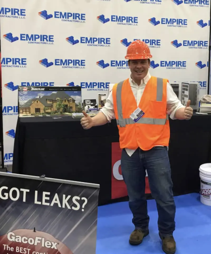 Man in orange hard hat and safety vest holding GacoFlex roof repair product at Empire Contractors trade show booth in Cincinnati