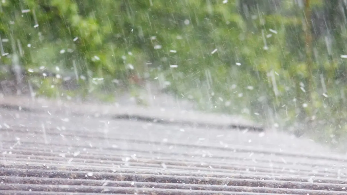 A residential roof being pelted by hail during a storm, highlighting potential damage risks such as dented shingles and leaks. Empire Contractors LLC provides expert hail damage roof repair and replacement services in Cincinnati, OH, and surrounding areas.