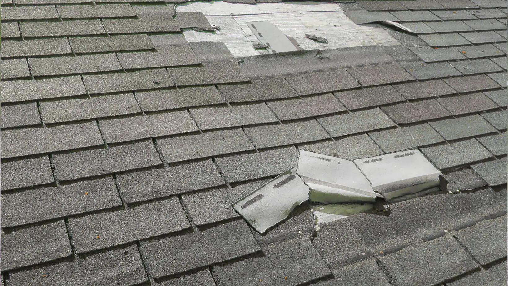A residential roof with visible wind damage, including missing or lifted shingles. Empire Contractors LLC provides expert wind-damaged roof repair and replacement services in Cincinnati, OH, and surrounding areas.