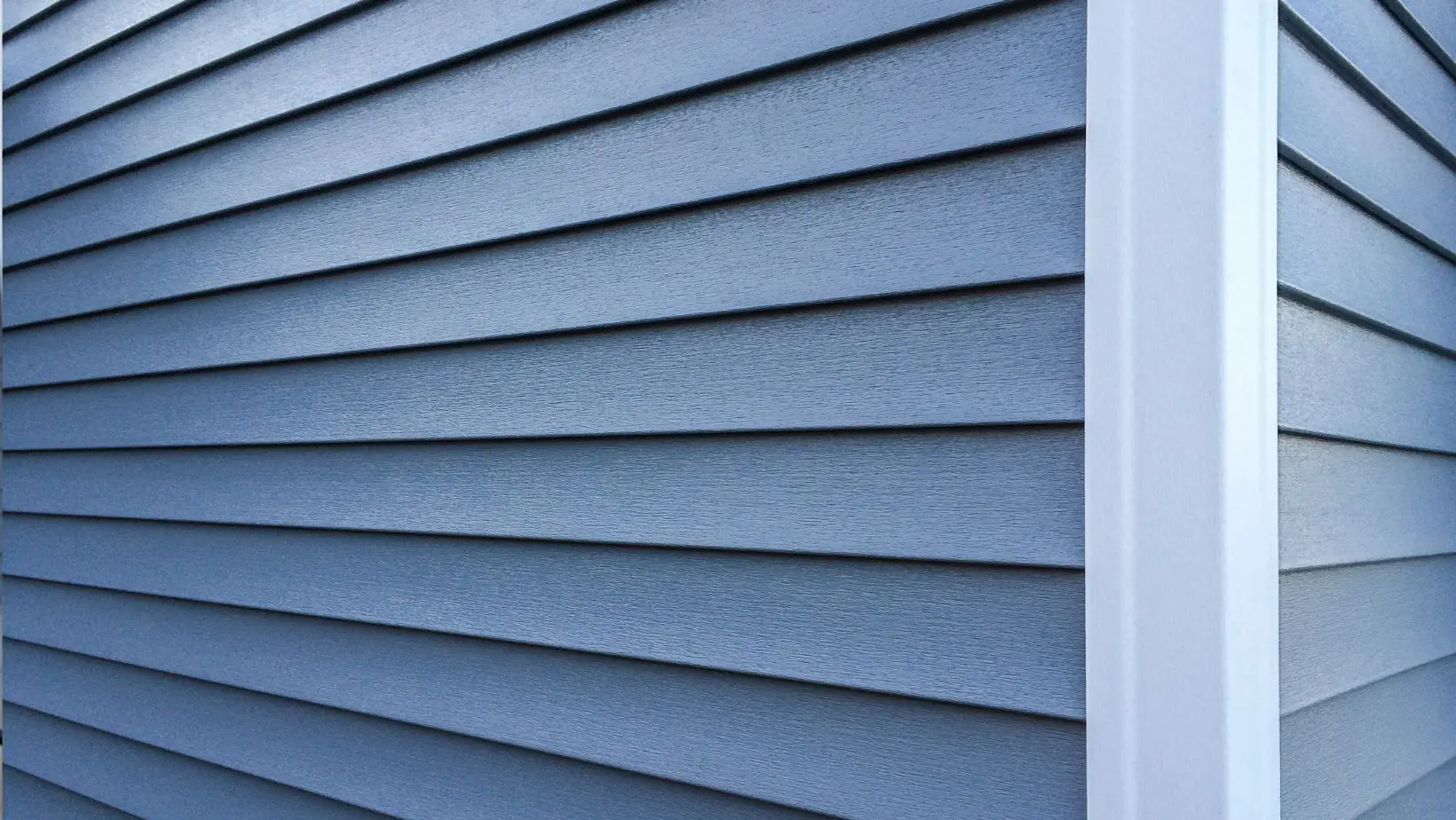 Close-up of modern blue vinyl siding on a home exterior, showcasing durable, weather-resistant construction. Empire Contractors specializes in professional siding installation for improved curb appeal and energy efficiency.