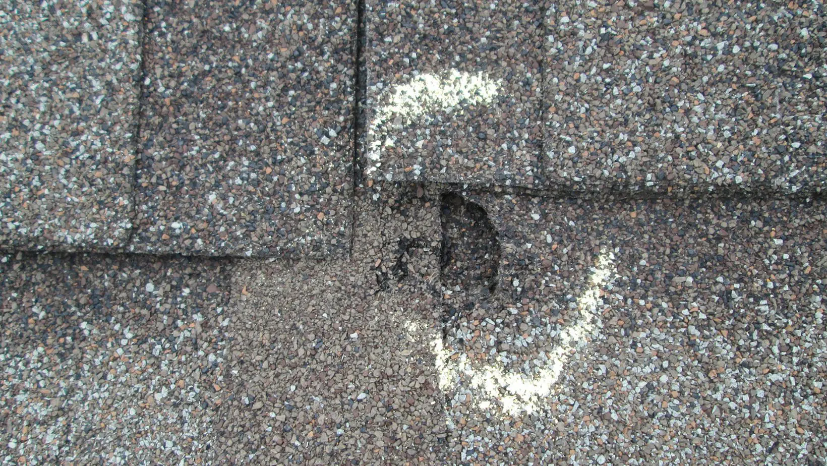 A residential roof with visible hail damage, including dented shingles and granule loss. Empire Contractors LLC provides expert hail-damaged roof repair and replacement services in Cincinnati, OH, and surrounding areas.
