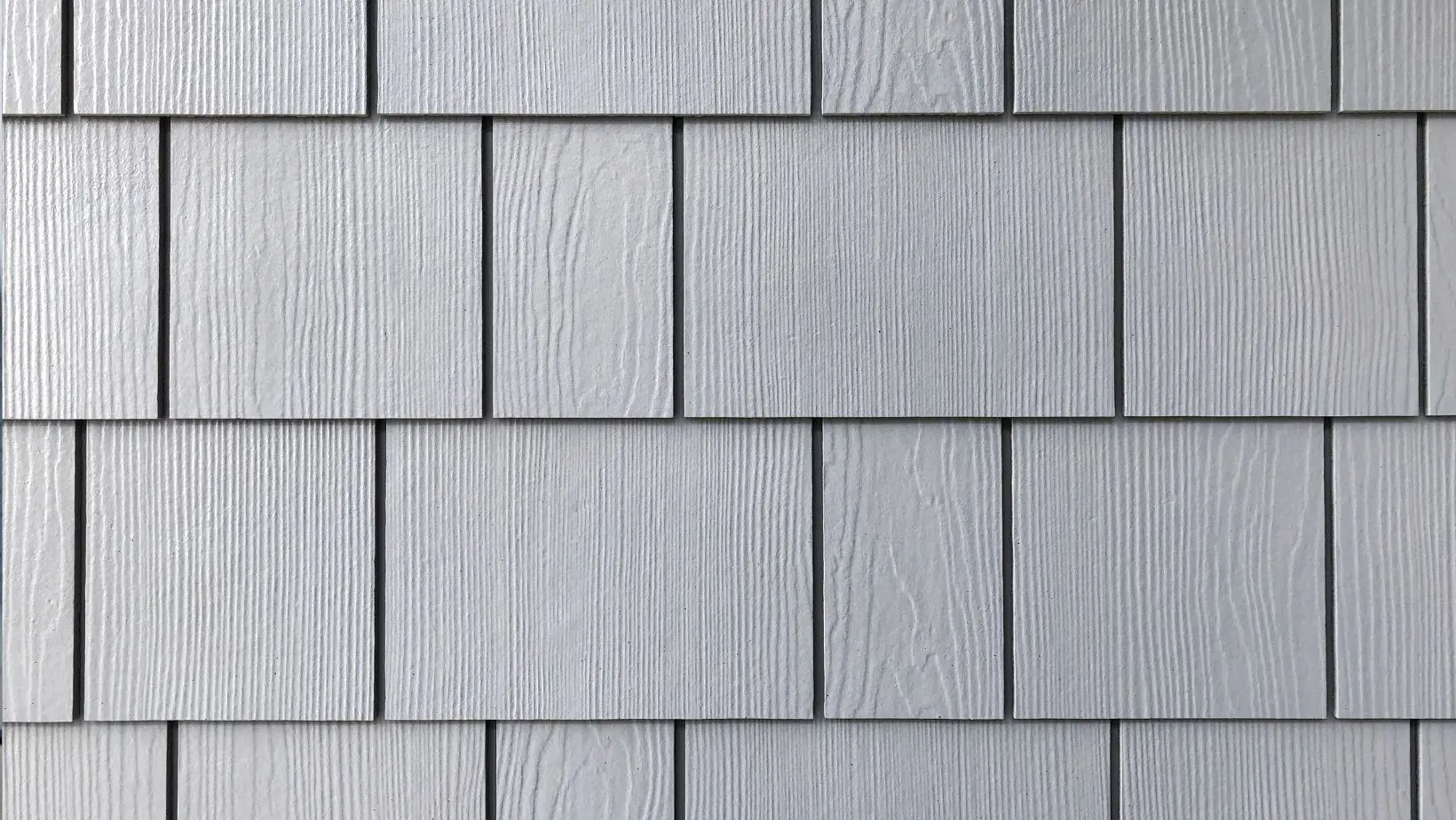 Close-up of gray shake and shingle siding with a wood grain texture, offering a classic and durable exterior finish. Ideal for adding character and weather resistance to homes. Empire Contractors specializes in professional shake and shingle siding installation for a timeless look.