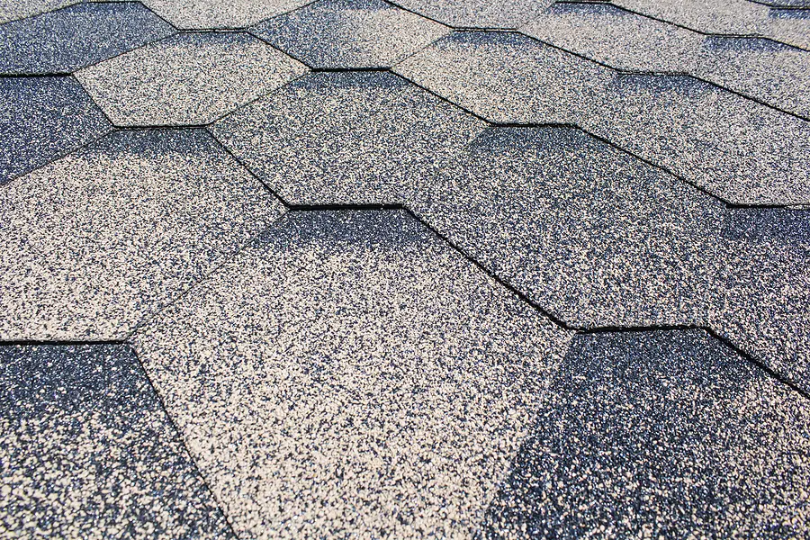 Close-up of asphalt shingle roof showing granule texture and overlapping shingles with shadows