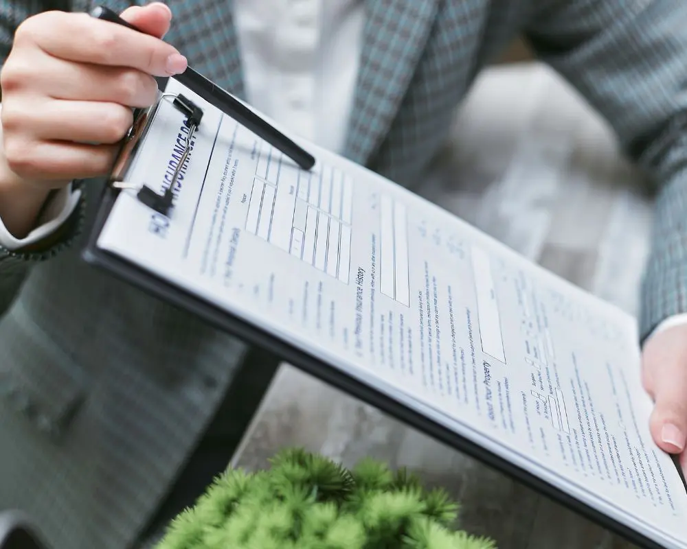 Inspector holding clipboard with roof inspection checklist and pen during property assessment