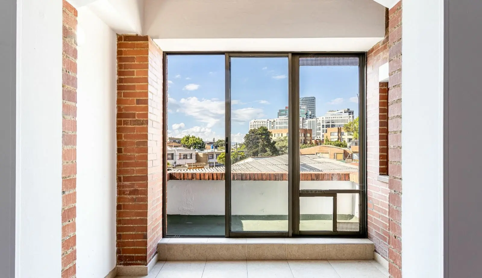 Modern sliding glass door with dark frame opening onto urban rooftop view of Cincinnati buildings and sky