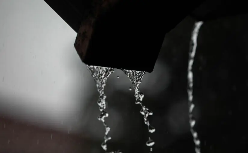 Close-up of rainwater flowing from gutters, showing water dripping off the edge during a heavy rainstorm.