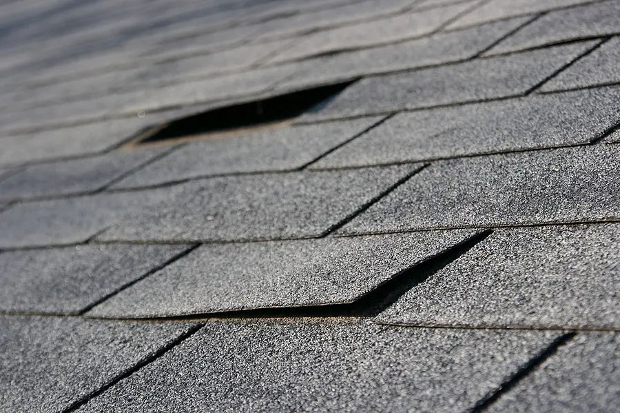Close-up of damaged asphalt shingles requiring roof replacement in Cincinnati