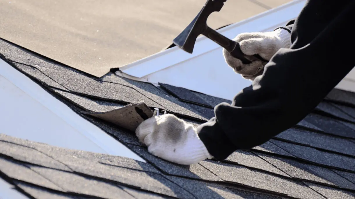 Worker in white gloves inspecting asphalt shingle roof for storm damage and missing shingles during roof inspection