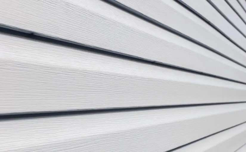 Close-up of horizontal vinyl siding panels with overlapping edges and dark trim lines creating shadow detail