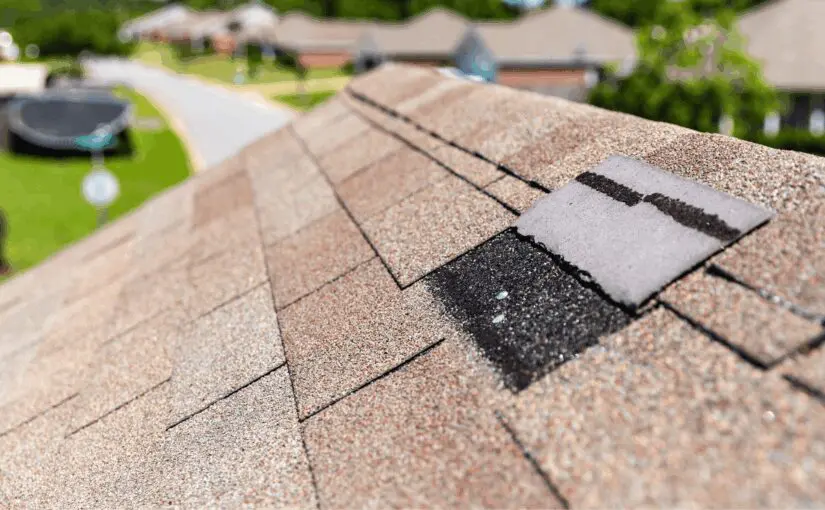 Close-up of asphalt shingle roof showing hail damage and missing shingles on residential home