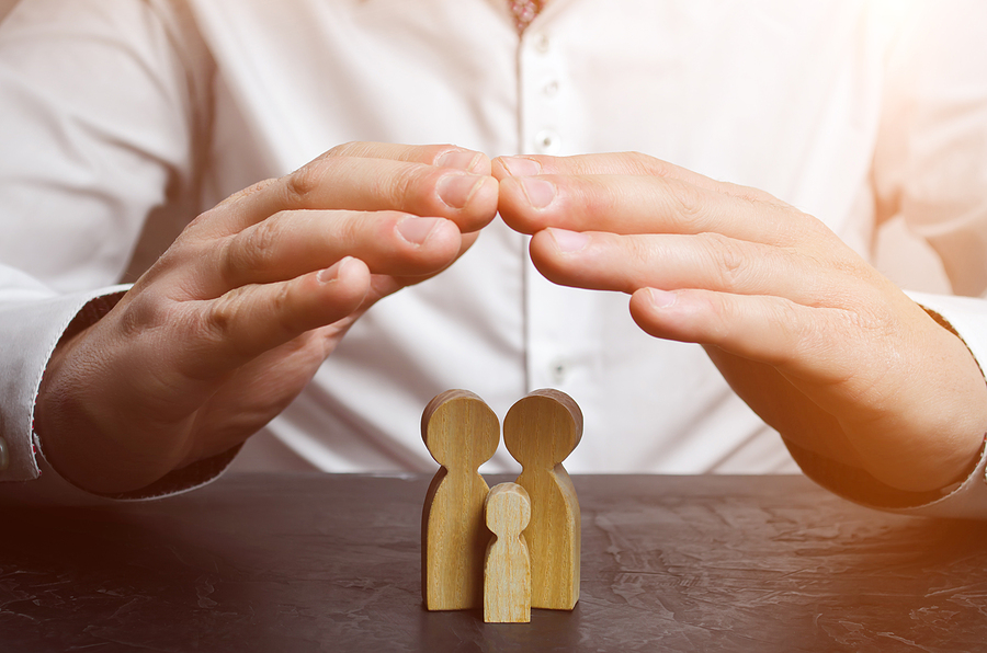 Insurance agent holds hands over family. The concept of insurance of family life and property. Family care and helping hand concept. Health insurance. Health care. Security and Property Protection