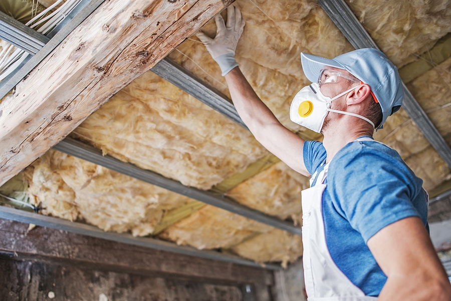 Contractor inspecting roof insulation for storm or water damage, part of the documentation process for homeowner insurance claims.
