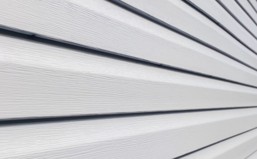 Close-up of horizontal vinyl siding panels with overlapping edges and dark trim lines creating shadow detail